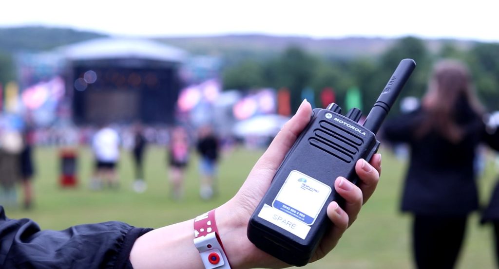 a womens hand holding a motorola radio at a festival
